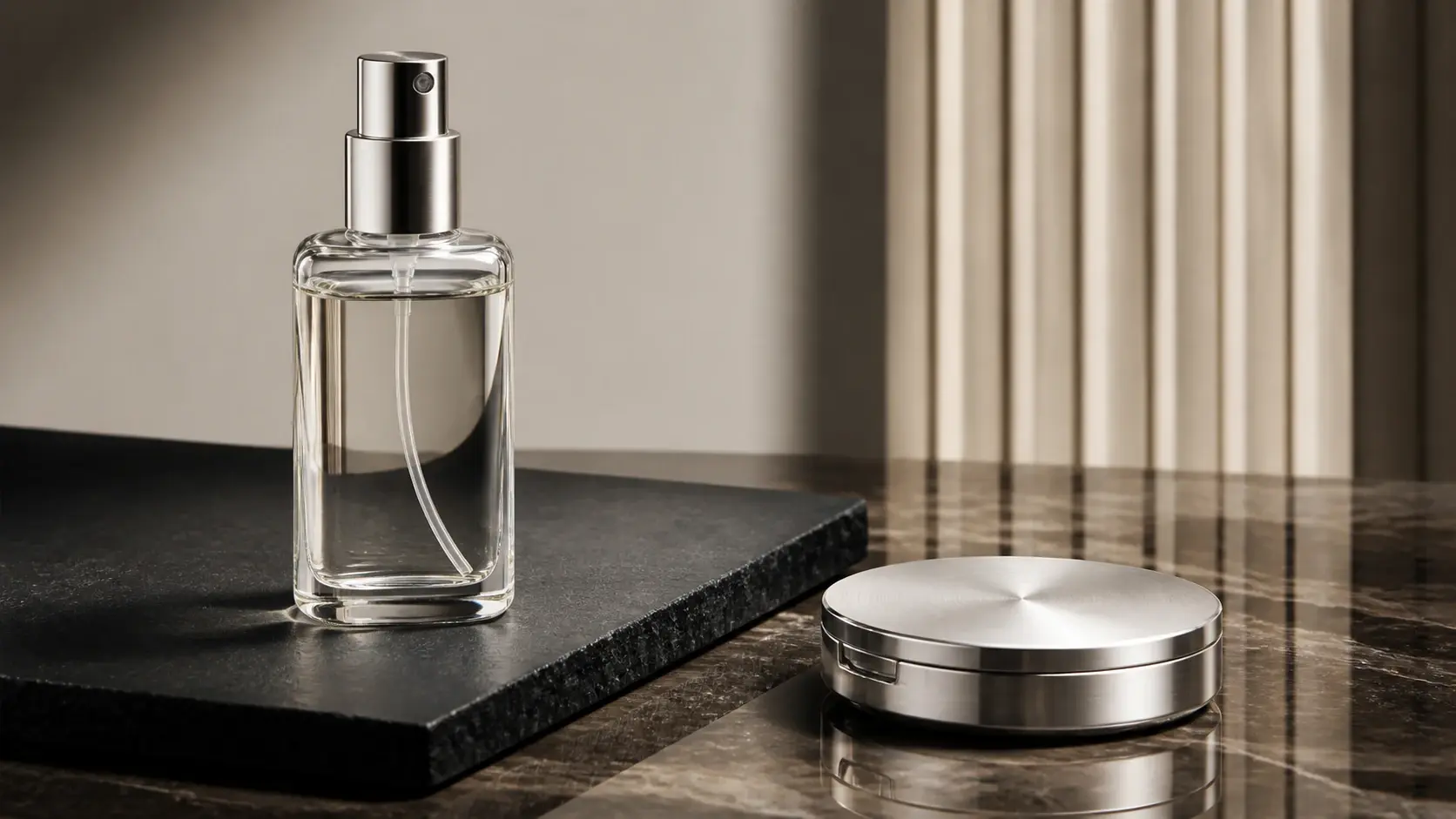 Perfume spray bottle and silver compact on a marble surface with beige backdrop