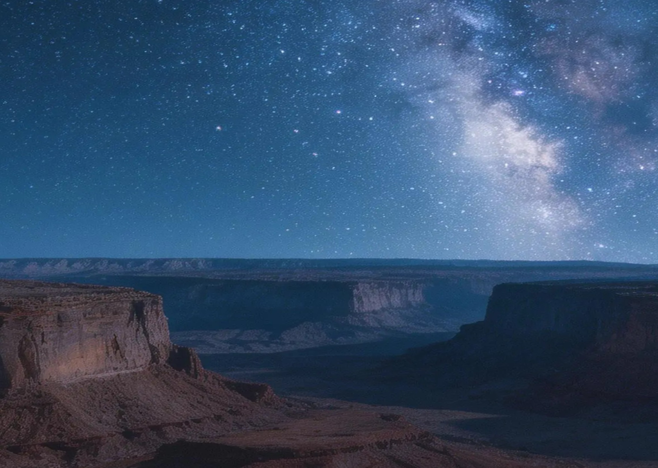 A time-lapse of stars rotating above a desert canyon