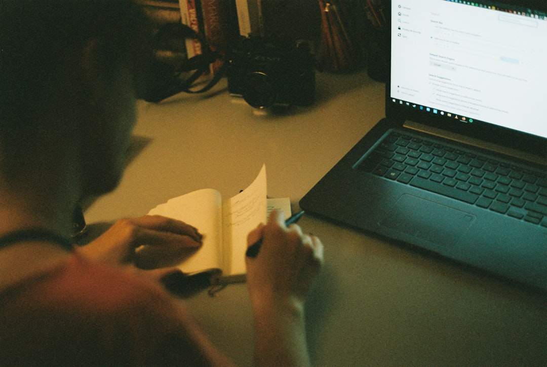 Une personne éditant un document texte sur un écran d'ordinateur avec un lecteur vidéo visible dans le coin