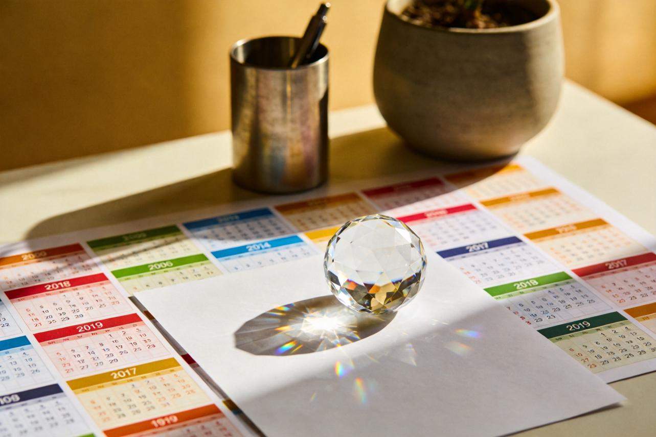 Crystal prism on blank paper over a colorful calendar spread