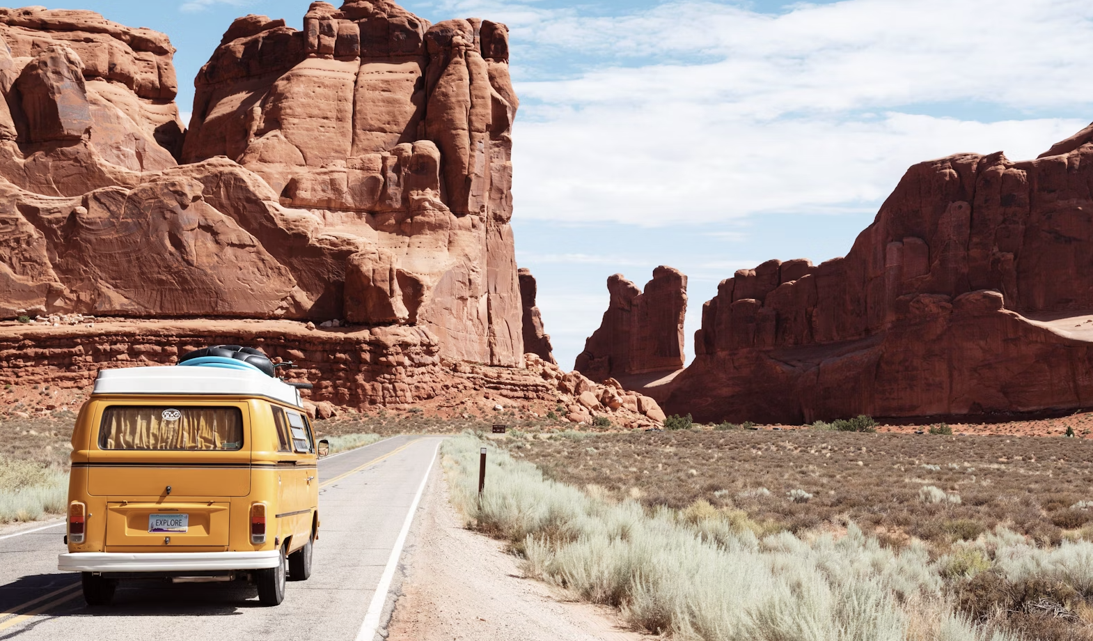 A person sitting on a cliff overlooking a mountain range, with a backpack and a map. The sun is setting, casting a warm glow over the scene. The image has a dreamy, adventurous feel.