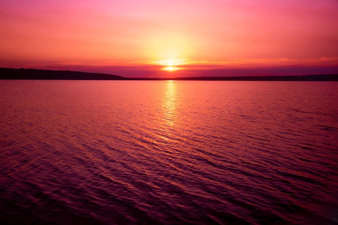A vibrant sunset over a calm sea, with hues of orange, pink, and purple reflecting on the water.