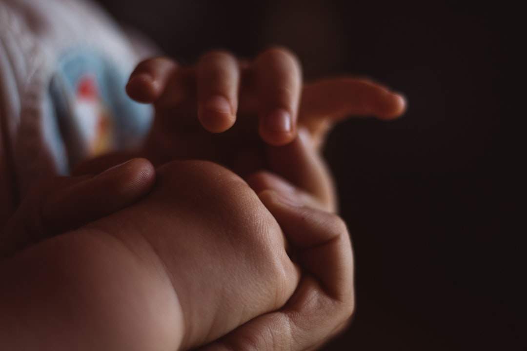 A close-up of a child's hand holding a parent's finger, symbolizing love and trust.