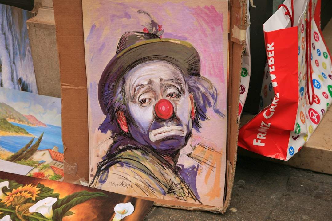 A single tear falling on a clown's painted face.
