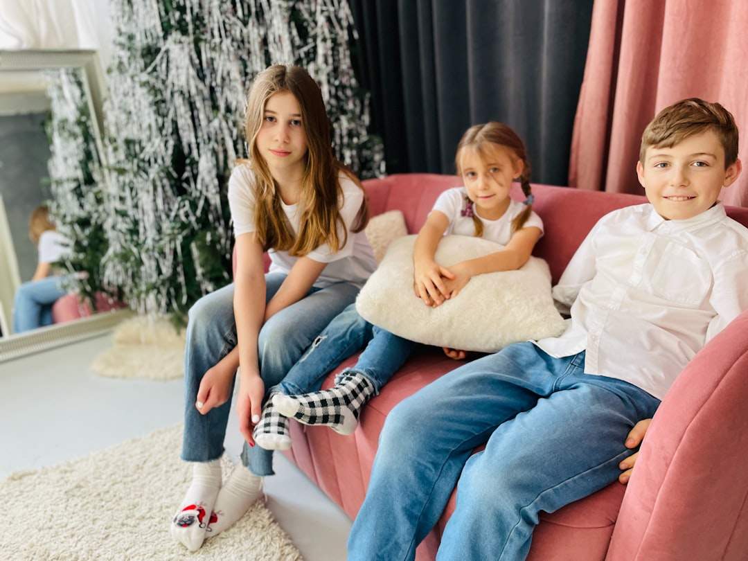 A happy family is sitting on the sofa, with parents and children reading a book together.