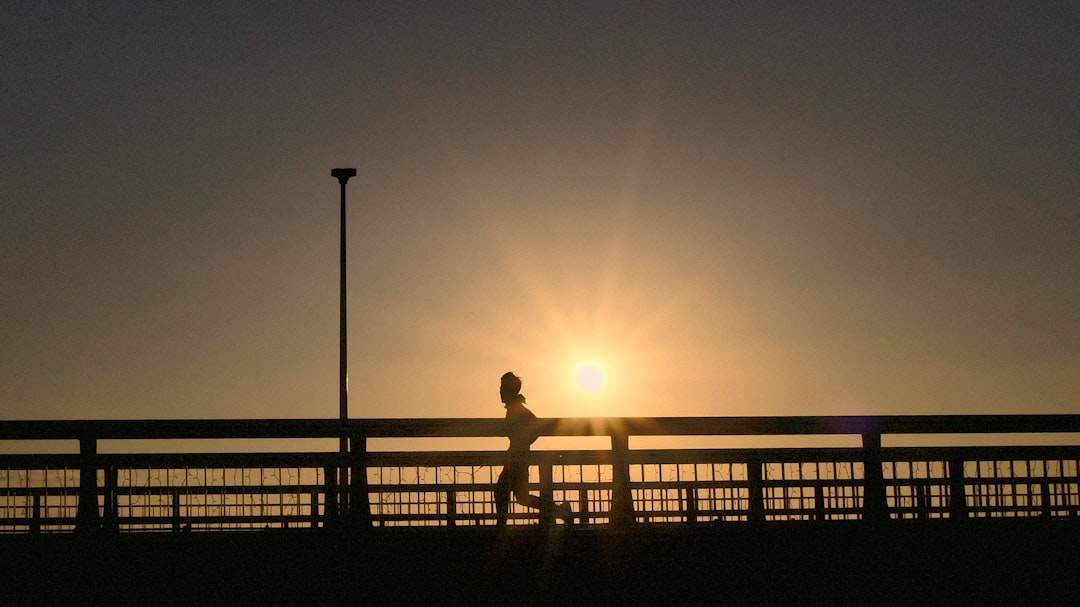背景に夕日が沈む中、ゴールラインを越えるランナーは、週を強く終えるためのプッシュを表しています。