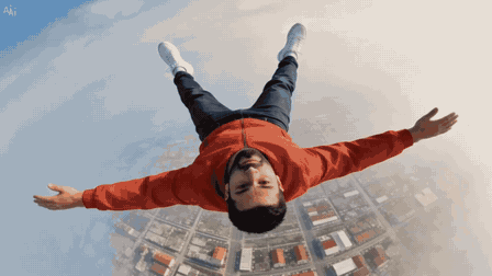 A man in a red jacket falls on his back toward a city seen from above; over fifteen seconds the picture turns from a photograph into folded paper, then into a pencil drawing of the streets, then into a 3D cartoon city under a blue sky, while he stays in the middle of the frame.