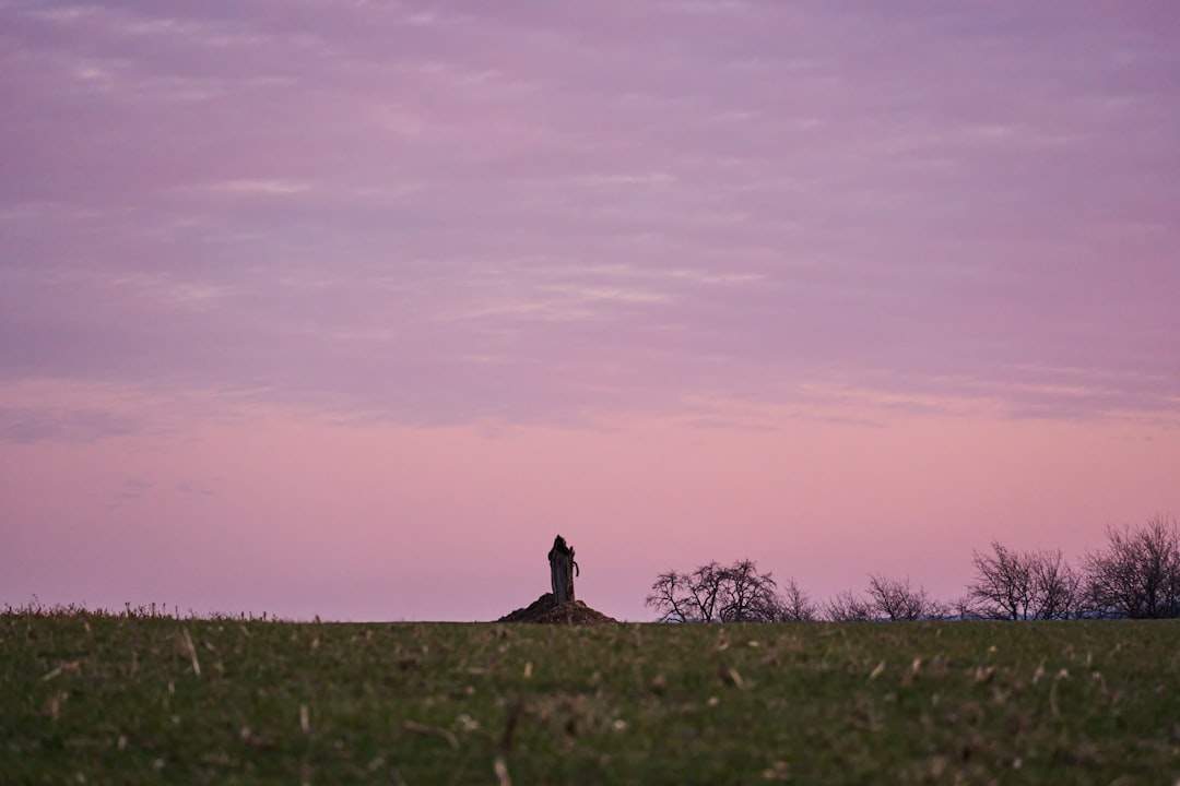 A person sitting on a hill, silhouetted against a beautiful sunset.