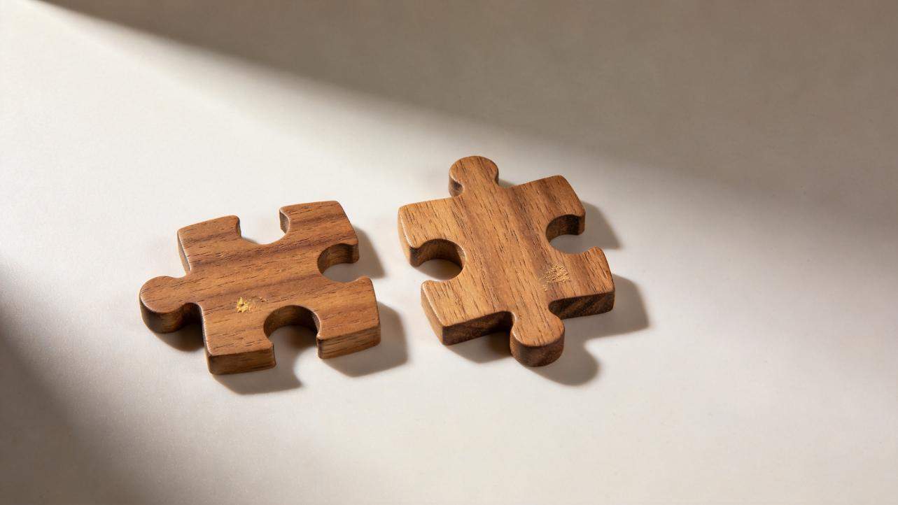 Two wooden jigsaw puzzle pieces lying apart on a white surface