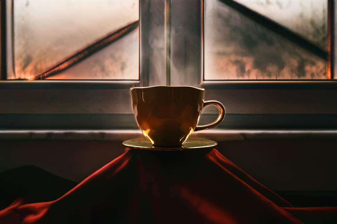 窓辺に置かれたコーヒーカップの静かなイメージで、朝の光が差し込み、平和でインスピレーションにあふれた一日の始まりを作り出しています。