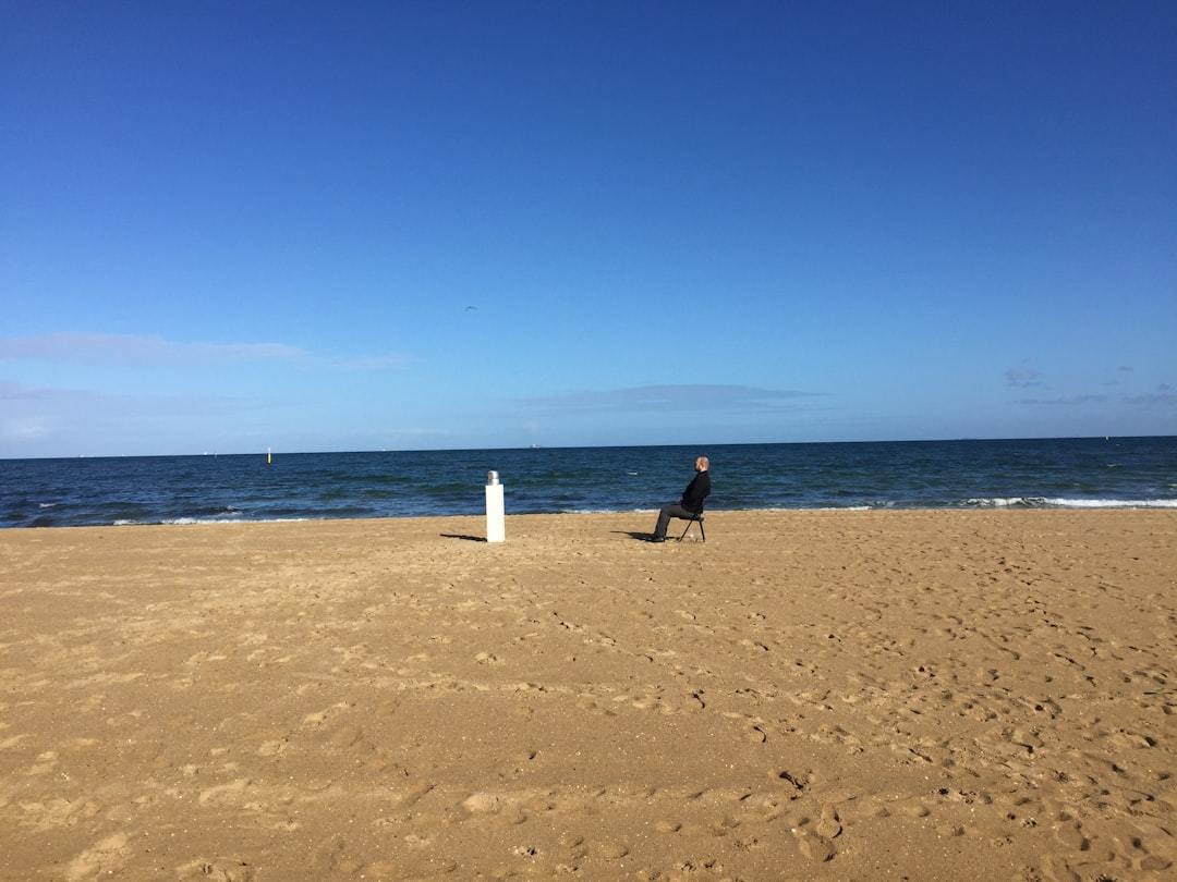 A person taking a selfie on the beach with the ocean in the background.